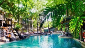 A pool surrounded by lush greenery and a waterfall.