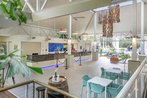 A spacious lobby with a reception desk, seating area, and a large window overlooking the parking area. - [Holiday Apartment] In Ramada Resort- Port Douglas (Port Douglas)