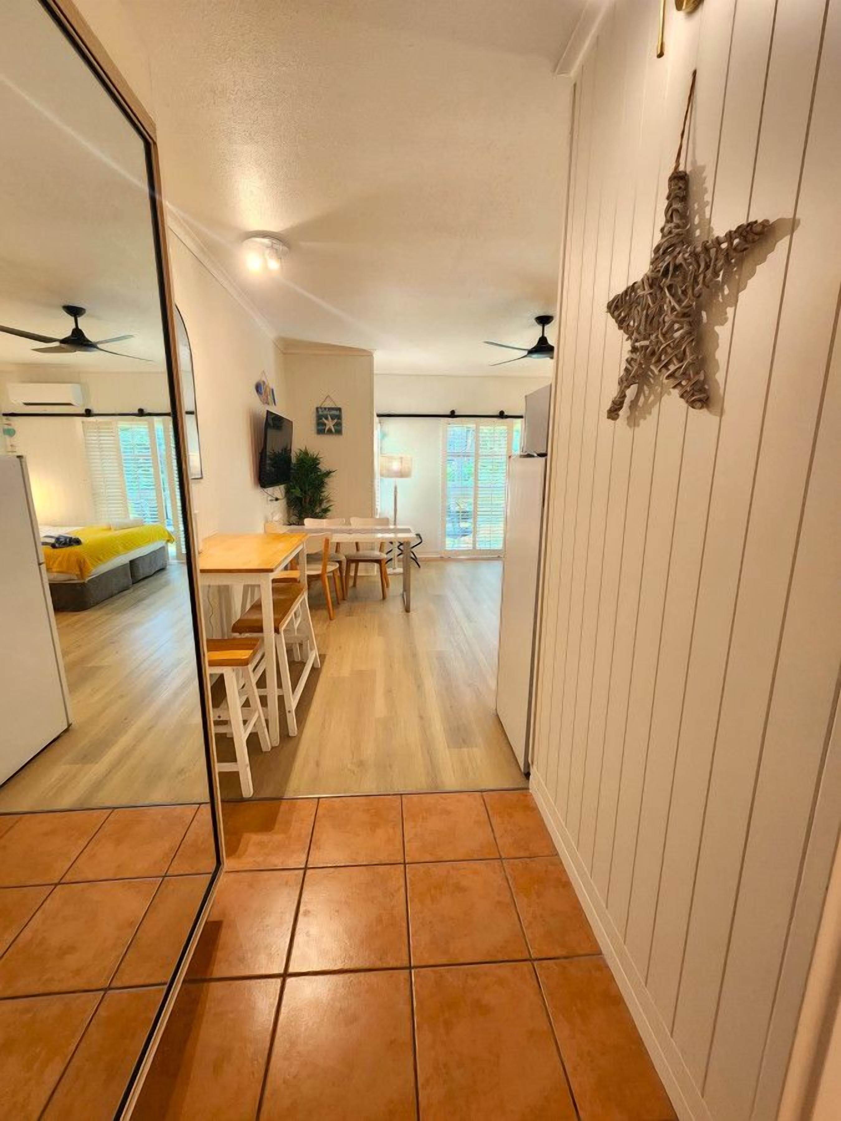 Un'ampia zona giorno con tavolo e sedie, una TV a parete e una ventola a soffitto.