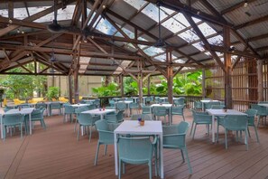 An outdoor dining area with tables and chairs, a wooden deck, and a metal roof structure. - [Holiday Apartment] In Ramada Resort- Port Douglas (Port Douglas)
