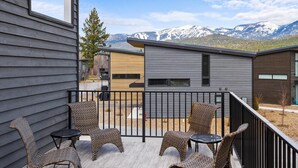 A balcony with wicker chairs and tables, overlooking a mountainous landscape. - Glacier State of Mind (Whitefish)