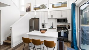 A modern kitchen with white cabinets, stainless steel appliances, and a central island with bar stools. - Glacier State of Mind (Whitefish)