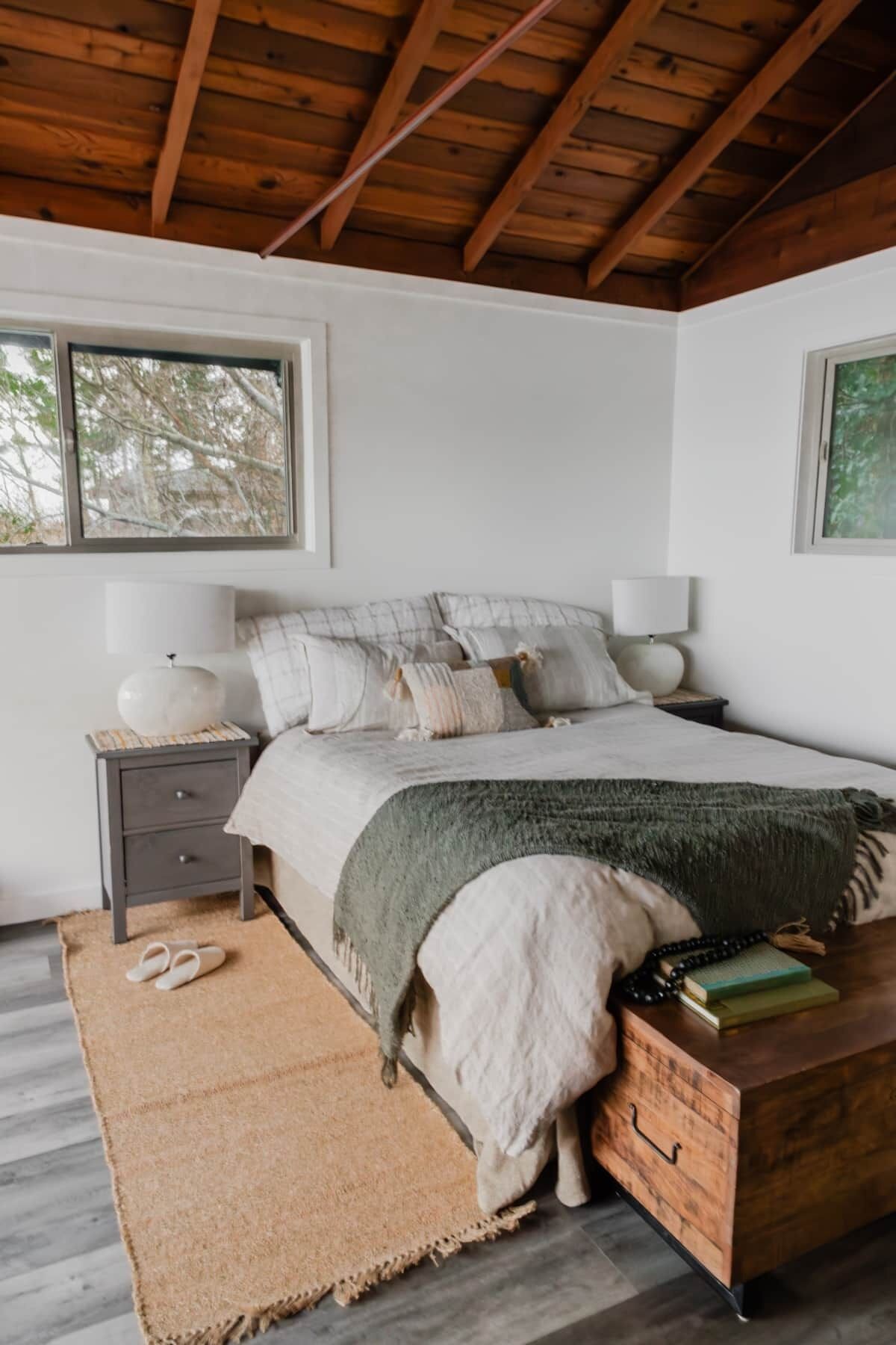 A bedroom with a bed, nightstands, a wooden chest, and a window.