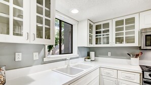 A modern kitchen with white cabinetry, a double sink, and a stainless steel stove. - Exceptional 2 Bed/2.5 Bath Marshside Villa in Gated Resort! 5-Min Bike Ride to Private Beach Access! (Fernandina Beach)