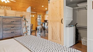 Una habitación con cama, un armario de madera y un comedor con sillas y una mesa.