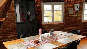 A dining area with a wooden table, black chairs, and a brick wall.