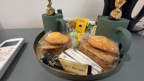 A tray with pastries, a coffee maker, and a small figurine on a table.