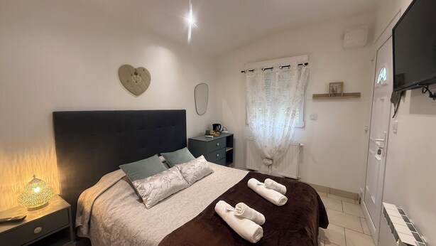 A neatly arranged bedroom with a bed, bedside tables, a nightstand, a mirror, a wall-mounted TV, and a window with curtains. - 🌿 Charming & relaxing stay in the heart of Burgundy 🌿 (Malay-le-Petit)