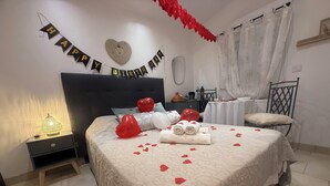 A bedroom with a bed, a nightstand, a dresser, a table, and a chair. There is a 'Happy Birthday' banner on the wall.