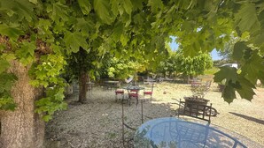 An outdoor seating area with tables and chairs, surrounded by trees and gravel. - 🌿 Charming & relaxing stay in the heart of Burgundy 🌿 (Malay-le-Petit)