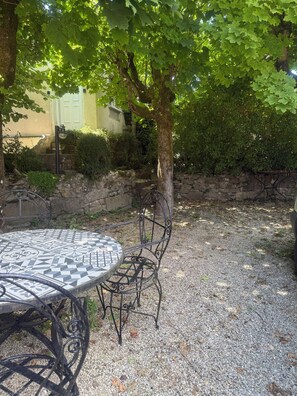 A patio with a round table and chairs, surrounded by gravel and a stone wall. - 🌿 Charming & relaxing stay in the heart of Burgundy 🌿 (Malay-le-Petit)