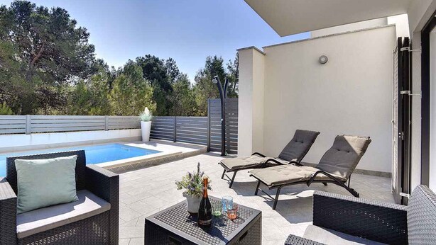 A rooftop patio with a pool, lounge chairs, and a table with a bottle and glasses. - Holiday home with terrace and pool (Ližnjan)