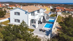 A modern two-story house with a swimming pool, surrounded by greenery and other houses. - Holiday home with terrace and pool (Ližnjan)