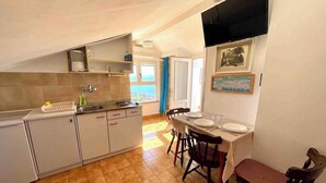 Una cocina compacta con comedor, que presenta suelo de baldosas, un fregadero y una mesa de comedor lista para cuatro comensales.