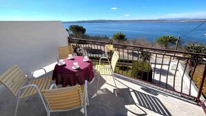 A balcony with a table and chairs, overlooking a scenic view of the sea and distant mountains. - Holiday apartment with balcony and air conditioning (Dramalj)