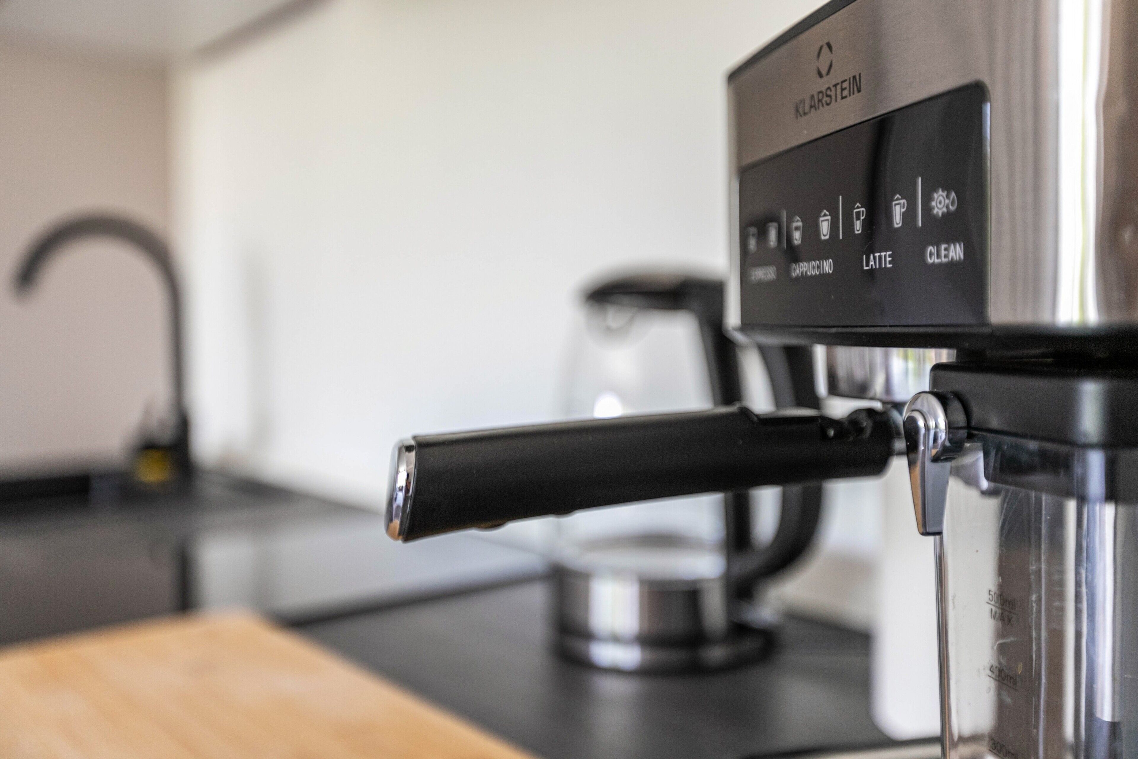 Une machine à café dotée d’un panneau de commande affichant les options pour préparer des cappuccinos, des lattés et pour lancer le cycle de nettoyage.