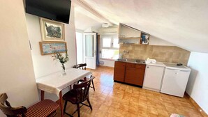 Une cuisine compacte avec des meubles en bois, un réfrigérateur blanc et un coin repas comprenant une table et des chaises.