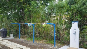 Un espace public extérieur doté d’une structure métallique bleue, qui pourrait être une structure d’escalade, et d’une fontaine à eau blanche.
