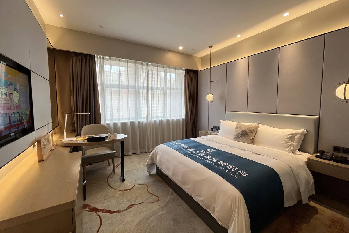 Ein modernes Hotelzimmer mit einem großen Bett, einem Schreibtisch und einem Fernseher.
