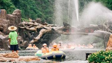 Un grupo de personas haciendo rafting en un río con una cascada al fondo.