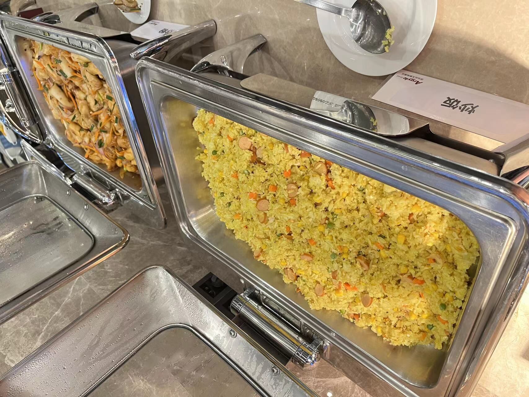 Un bufé con diversos platos, como arroz frito y una ensalada.
