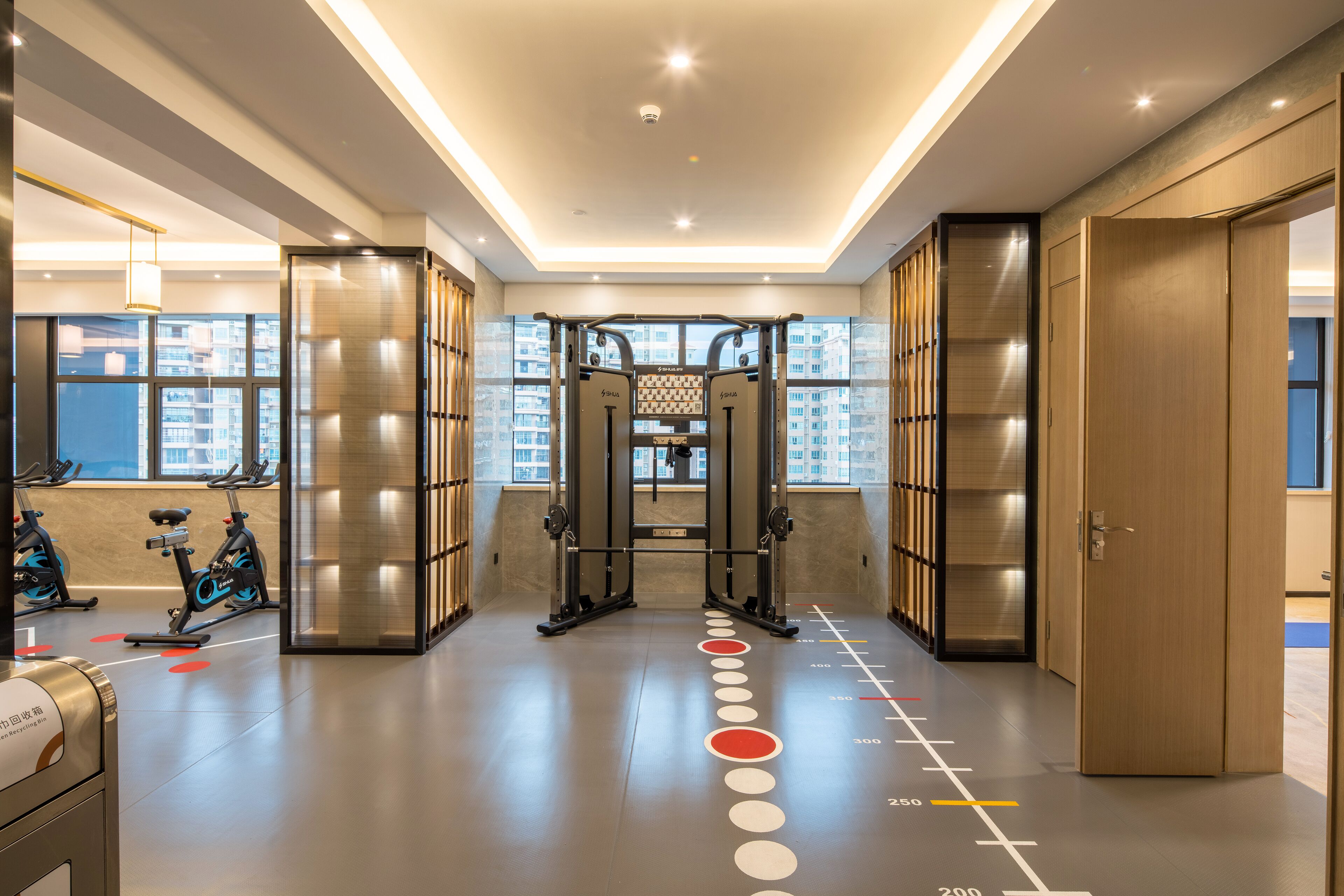 A modern gym with exercise equipment, a pull-up bar, and a fitness wall.