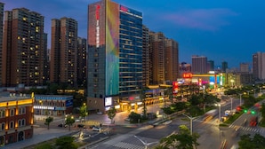 A high-rise hotel with a modern glass facade, surrounded by other tall buildings and a busy street with visible traffic lights and vehicles.