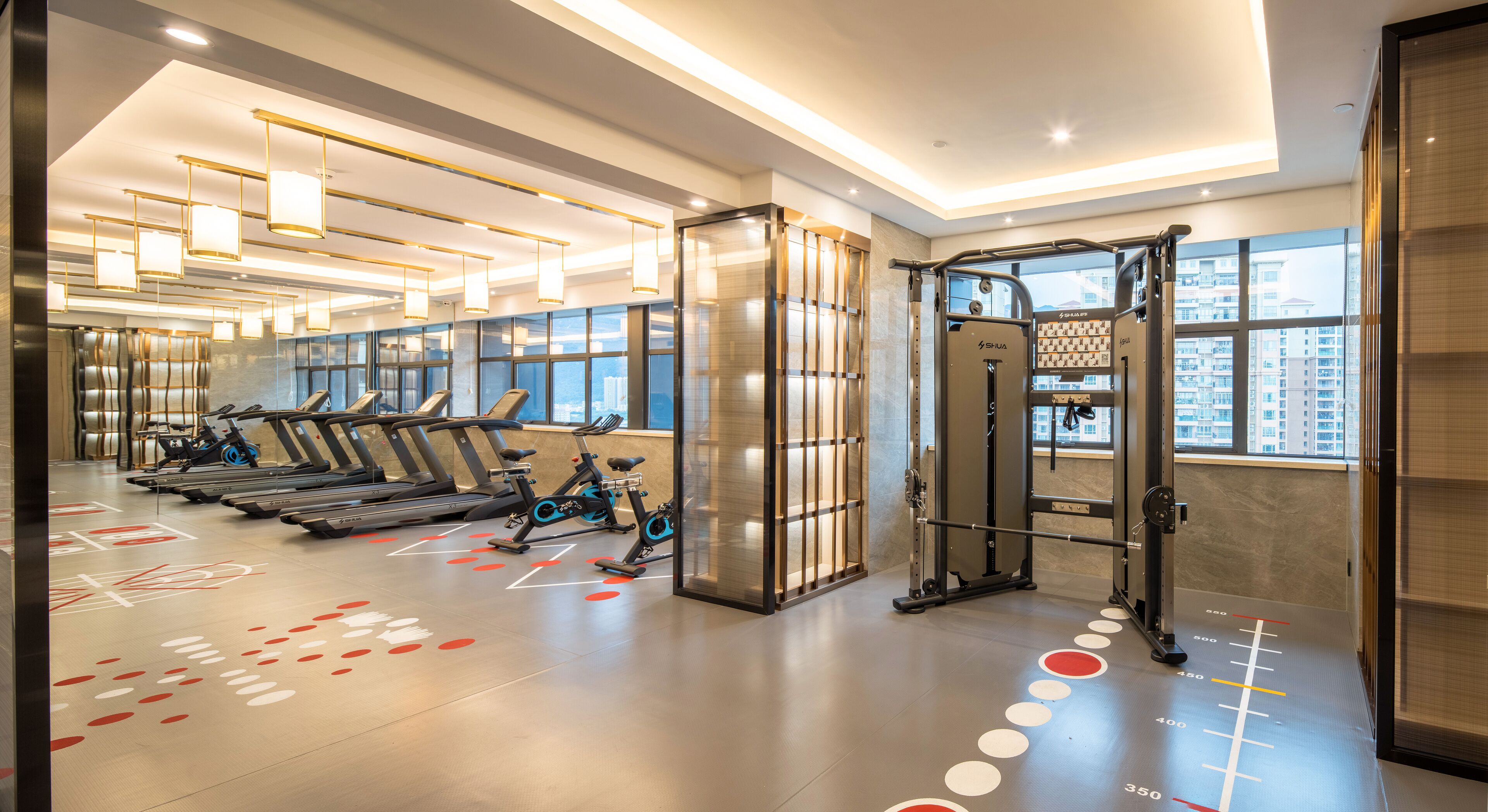 Un gimnasio moderno con cintas de correr, bicicletas estáticas y equipamiento de levantamiento de pesas.