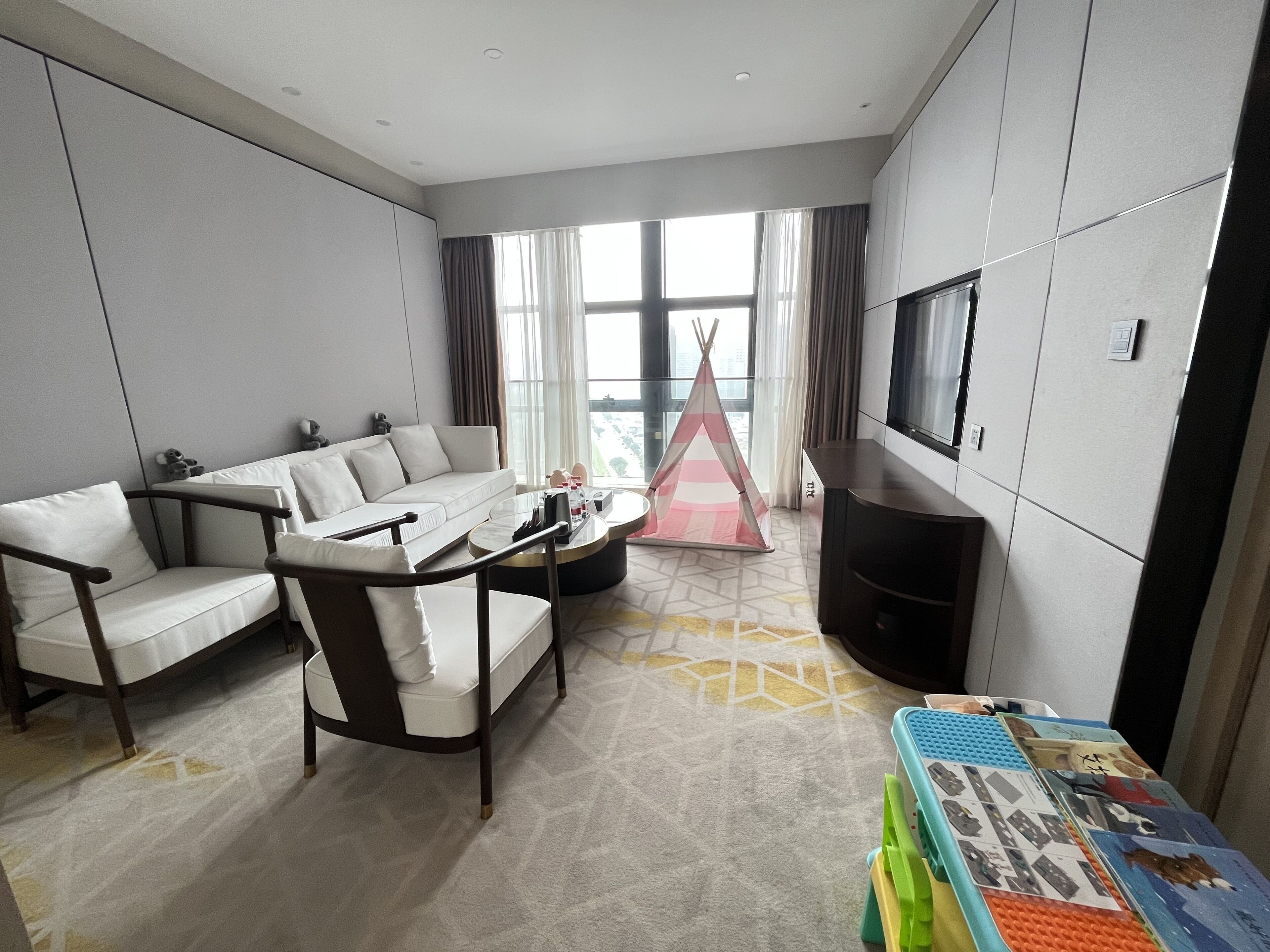 A modern living room with a sofa, a coffee table, a television, and a play area with toys.