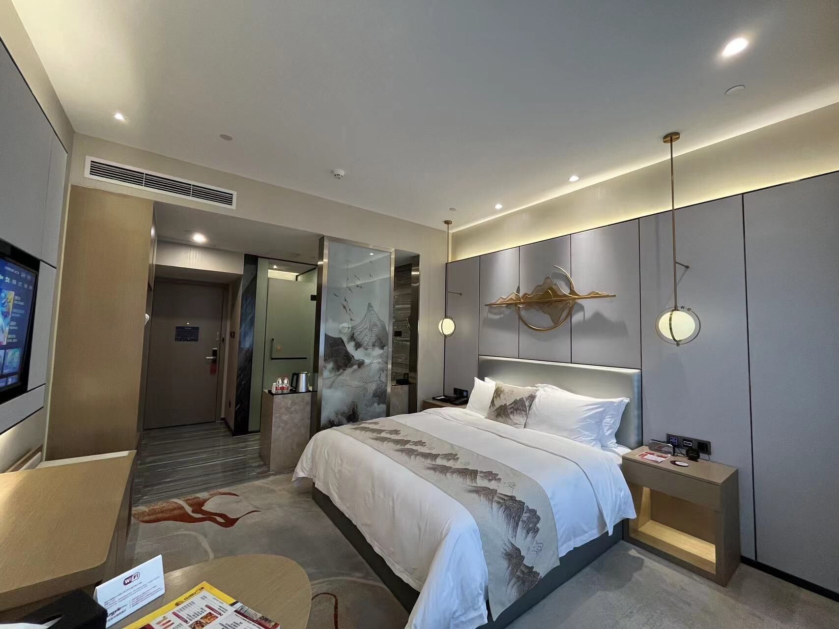 Una habitación de hotel moderna con cama, mesita de noche y televisión.