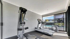 Ett gym med löpband, crosstrainer och en viktbänk.
