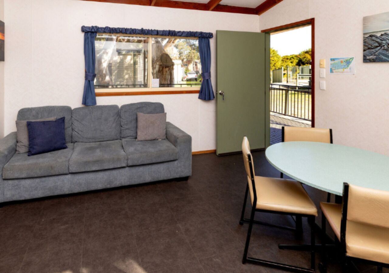 Una habitación con un sofá gris, una mesa redonda y sillas.