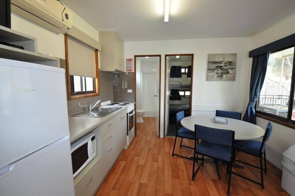 Cocina compacta equipada con refrigerador, estufa, microondas y pileta. Cuenta con un comedor con mesa y sillas.