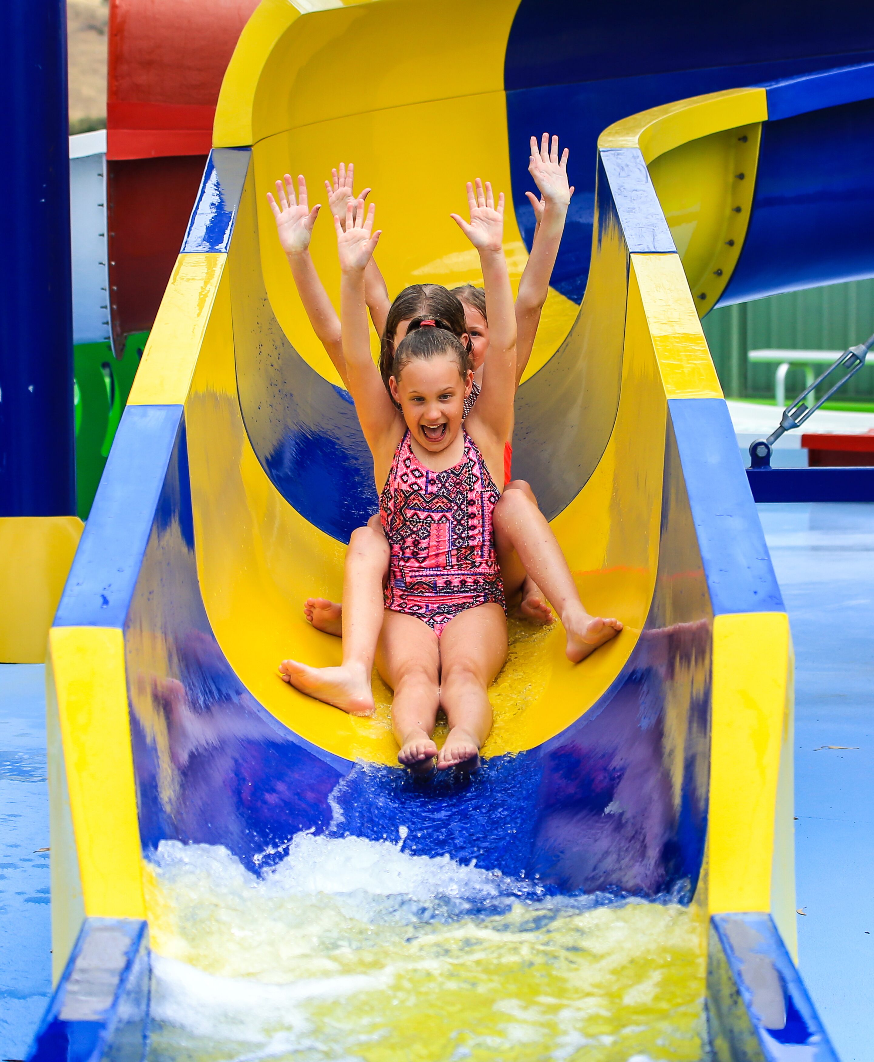 A child sliding down a yellow and blue water slide.