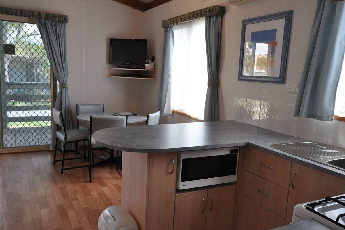 Una cocina compacta con comedor, un televisor montado en la pared y vistas al exterior.