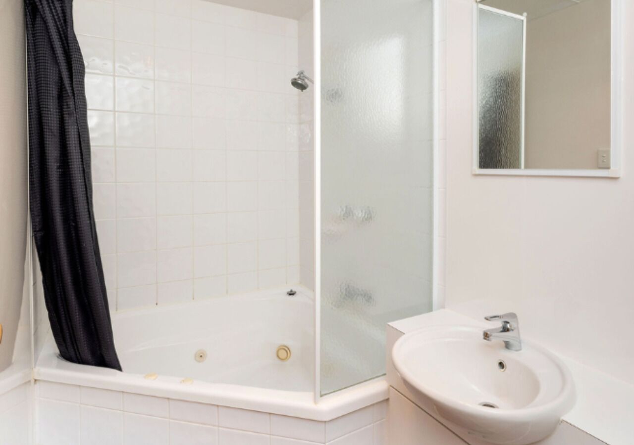 A modern bathroom with a glass-enclosed shower, a white sink, and a mirror on the wall.