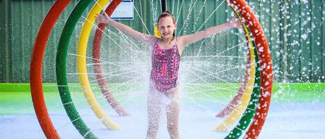 A person standing in a water play area with colorful rings.
