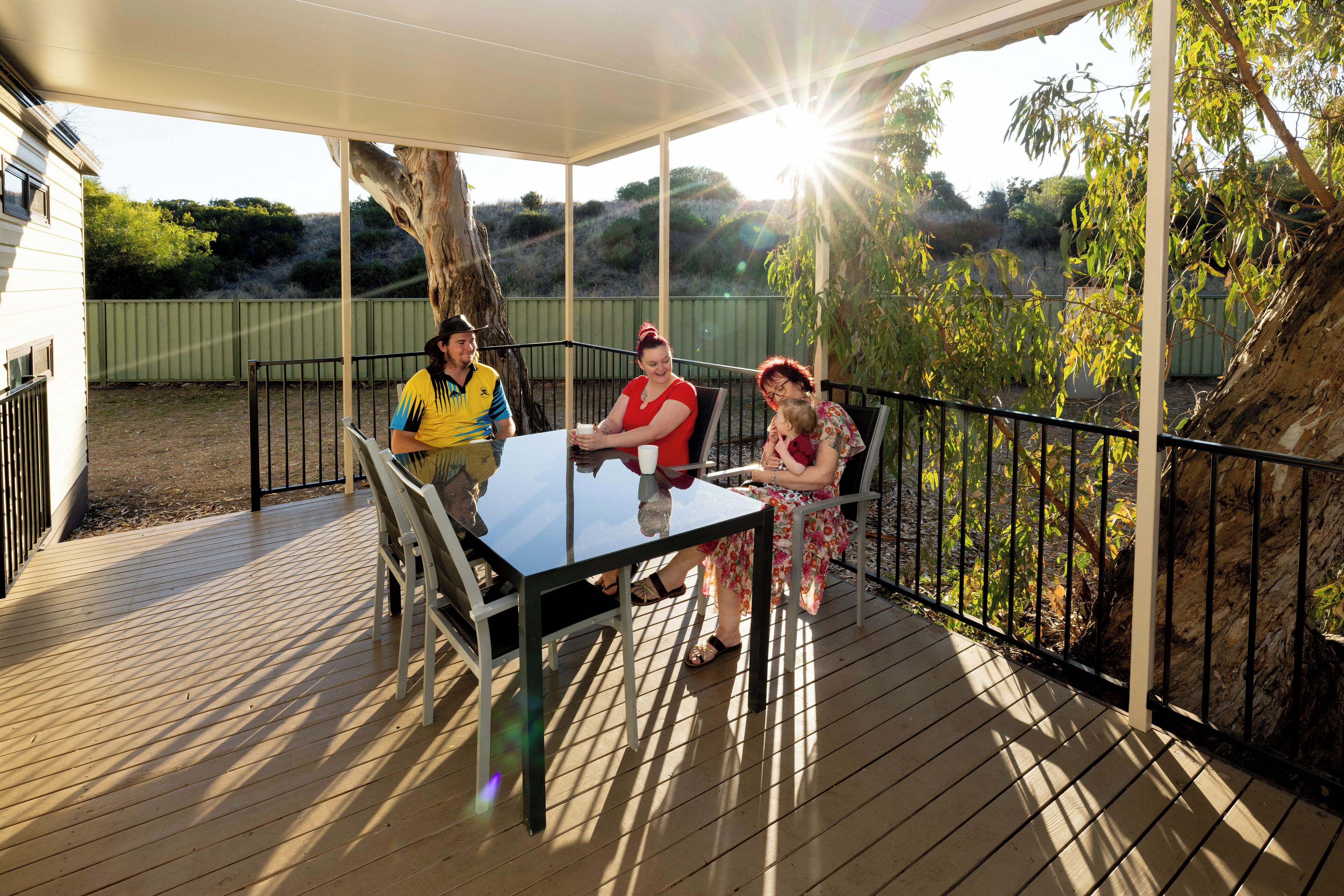 A covered outdoor area with a table and chairs, surrounded by a wooden deck and metal railings.