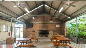 Un patio interior con paredes de ladrillo, una chimenea y mesas de picnic de madera.