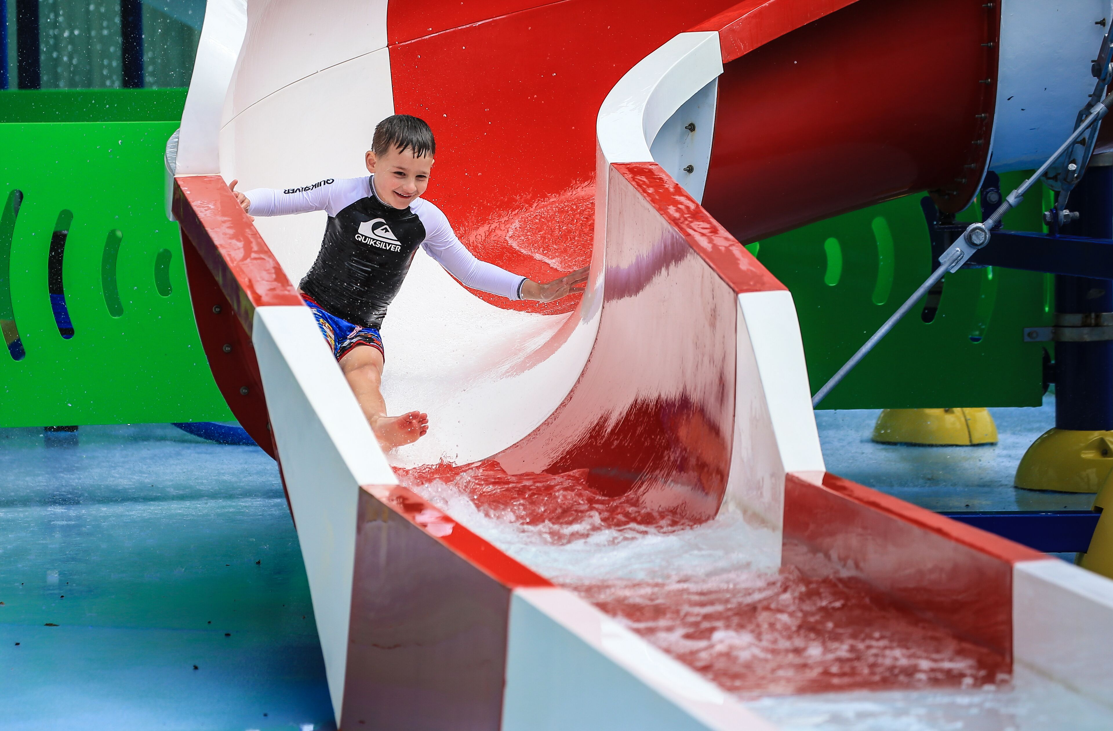 A child sliding down a red and white water slide.
