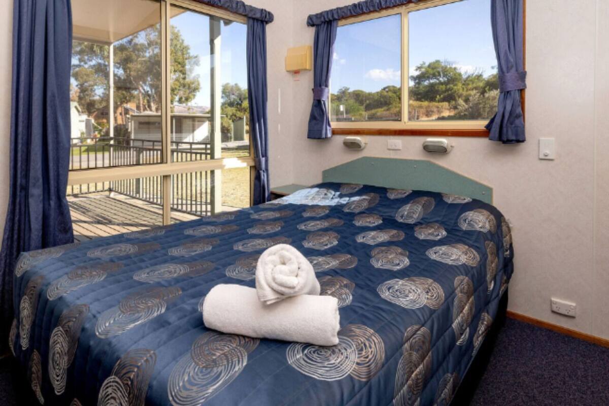 Un dormitorio con cama, ventana con cortinas y vista al exterior.