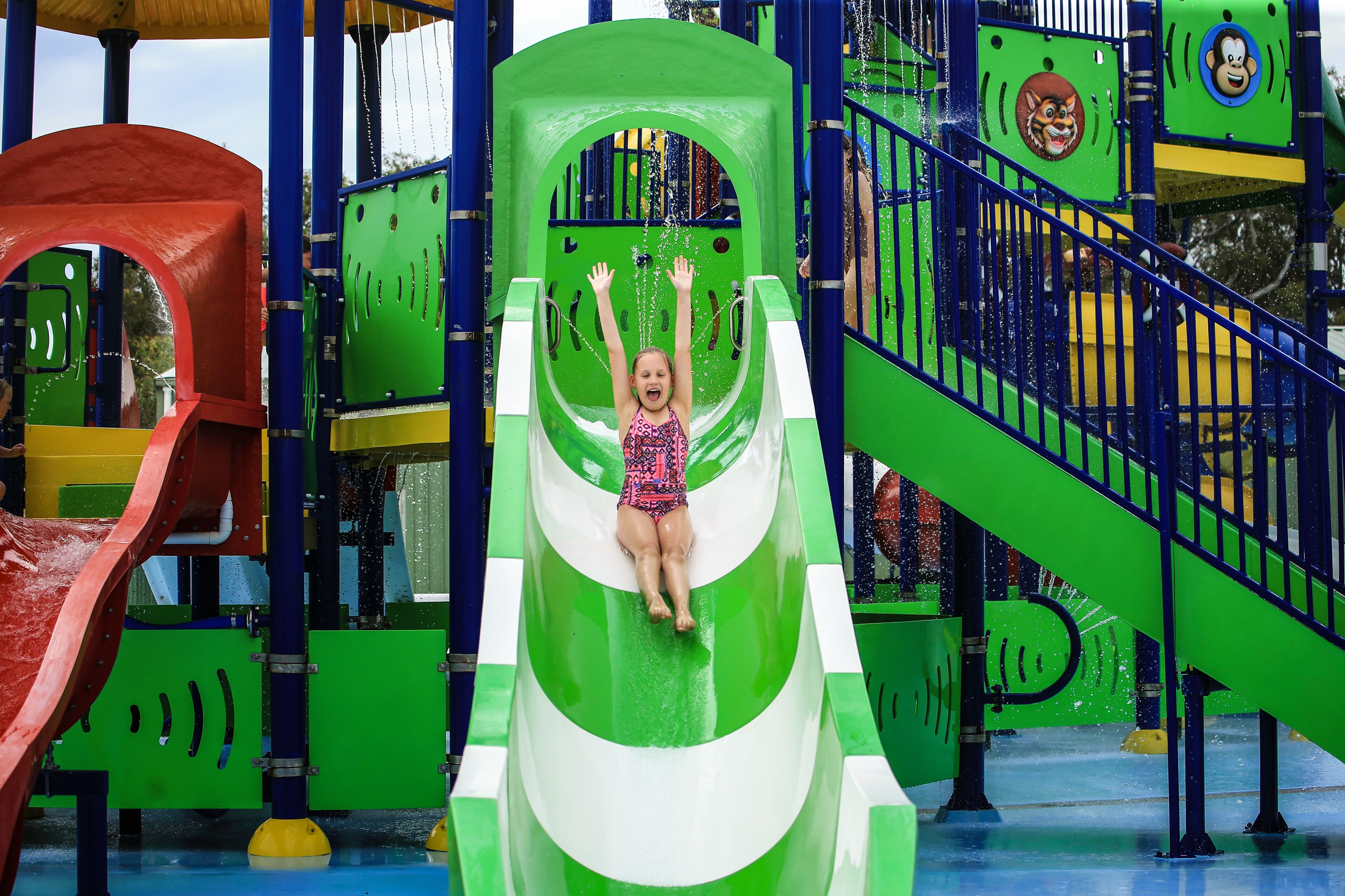 A child on a green water slide at a water park.