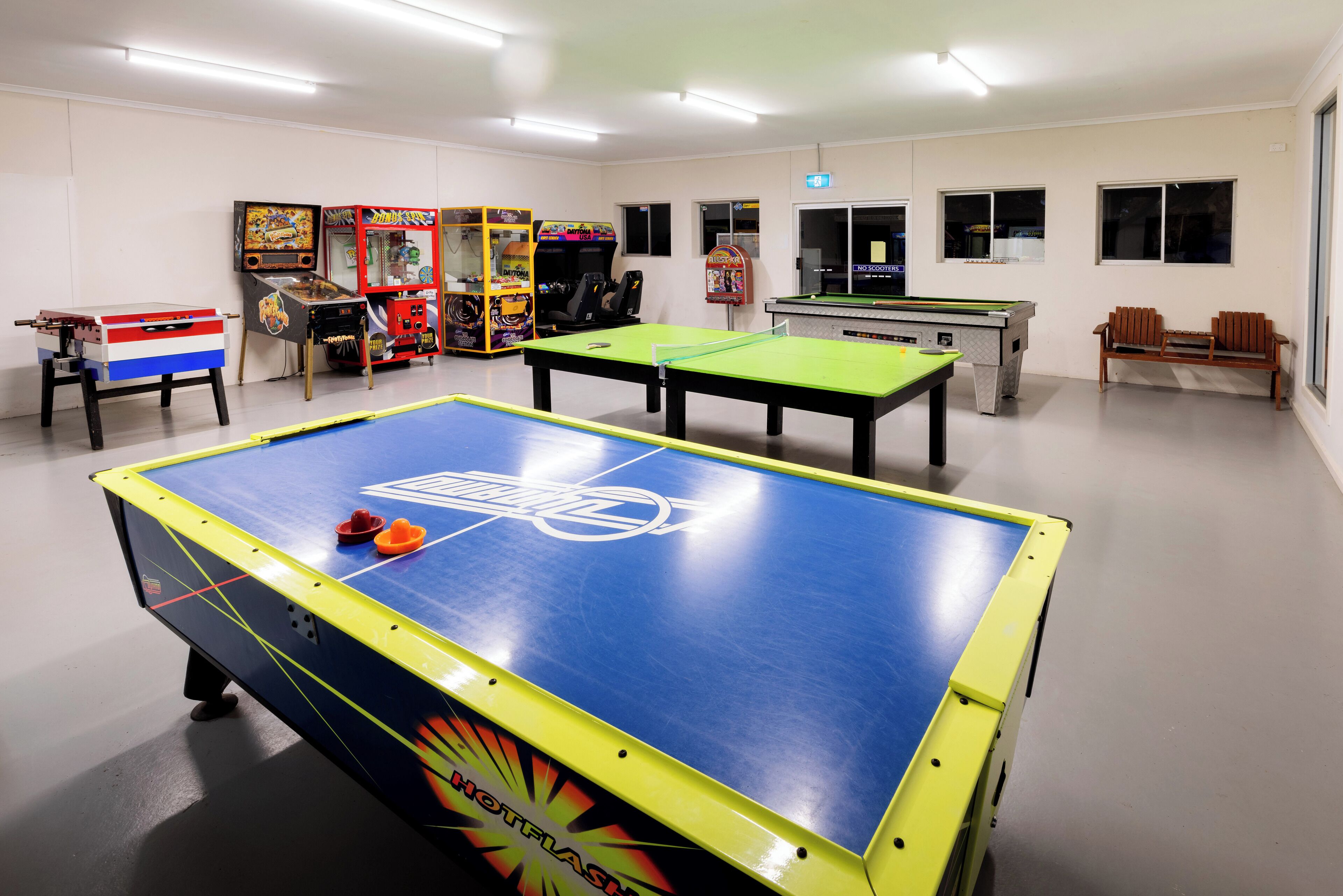 A room with multiple foosball tables, arcade games, and a pool table.