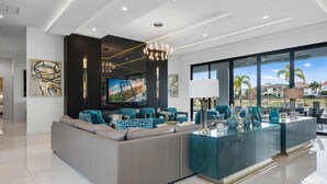 A modern living room with a large sectional sofa, a glass coffee table, and a television. - Legends Palazzo: Theater, Arcade, Private Pool, Free Water Park, Golf View (Kissimmee)