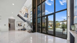 A spacious lobby with a modern staircase, large glass doors, and a view of the outside. - Legends Palazzo: Theater, Arcade, Private Pool, Free Water Park, Golf View (Kissimmee)