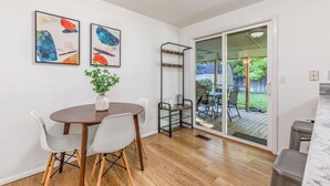 A dining area with a wooden table and chairs, a potted plant, and abstract artwork on the wall. - Cozy Boise Gem: Private Yard, Game Room & Workspace
 (BOISE)