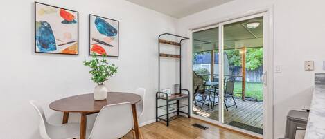 A dining area with a wooden table and chairs, a potted plant, and abstract artwork on the wall.