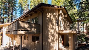 Une cabane en bois à deux étages, dotée d’un balcon et entourée d’arbres.