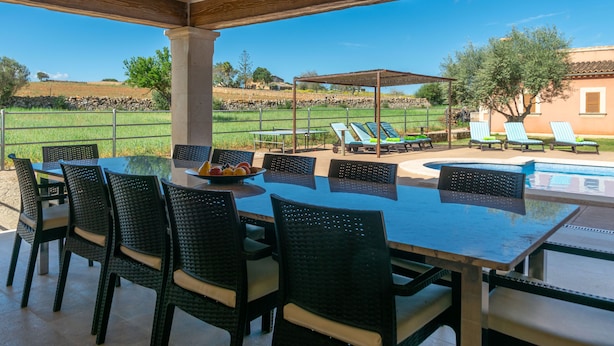 Un espace extérieur aménagé pour les repas, avec une piscine et des chaises longues.