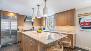 Eine moderne Küche mit Holzausstattung, Edelstahlgeräten und einer zentralen Kochinsel mit Barhocker.